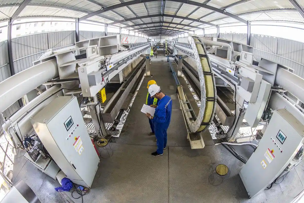 Two Loway automated filter presses running in parallel inside an industrial hall, each with its own PLC cabinet at the operator side