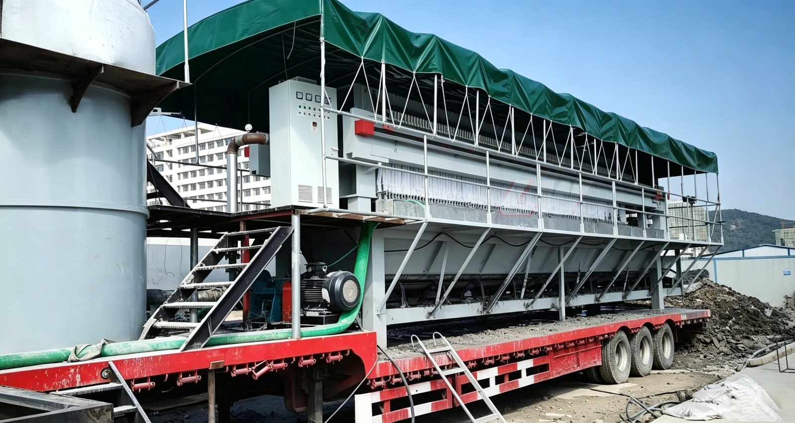 Loway mobile filter press on a truck-mounted frame for municipal sewage treatment with green weather canopy and slurry hoses