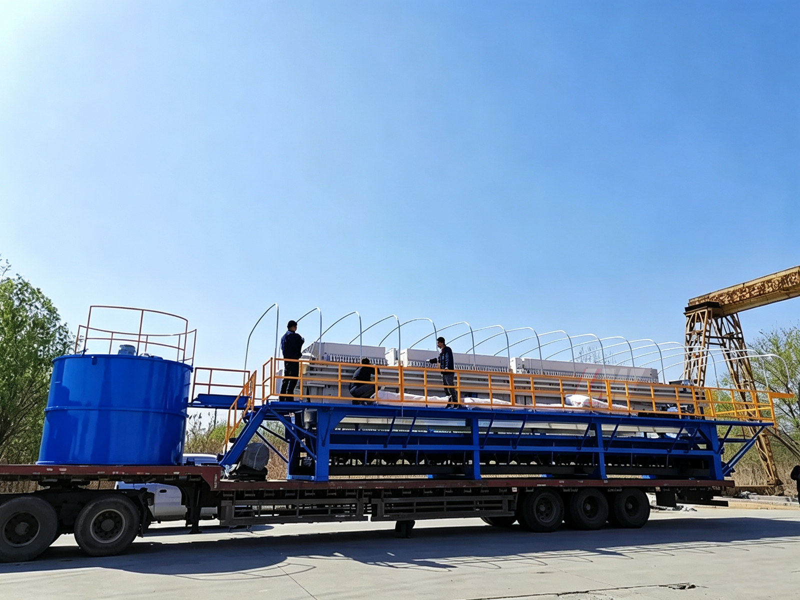 Loway mobile filter press for on-site dewatering with blue conditioning tank and truck-mounted frame at an industrial site