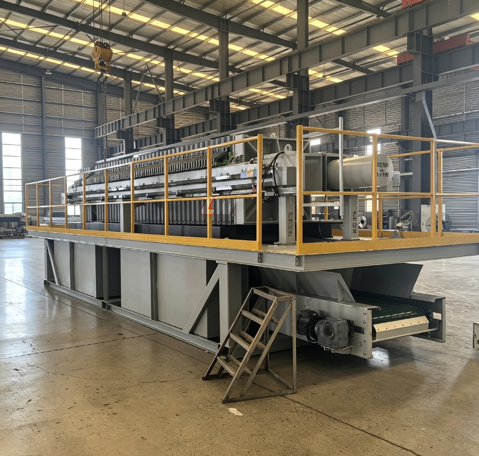 Loway skid-mounted filter press inside the factory, with yellow safety railings, feed pump and control panel on a single transportable frame